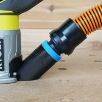 Black hose adapter with blue grip band attached to Ryobi trim router, orange hose connected to adapter port
