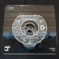 10-inch square acrylic router base plate mounted on a Bosch 1617 router, top view showing clear cast acrylic with circular center opening and mounting holes