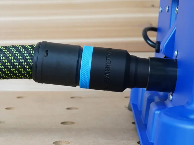 Black hose adapter with blue band attached to Kreg foreman pocket-hole machine, braided hose connected to adapter port