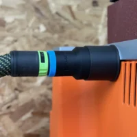 Black hose adapter with green and blue identification bands connected to a Ridgid oscillating edge sander with orange housing