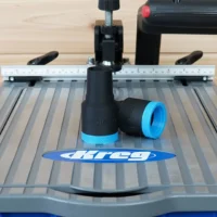 Black hose adapter with blue grip band attached to rear dust port of Kreg Foreman pocket-hole machine, shown on work surface