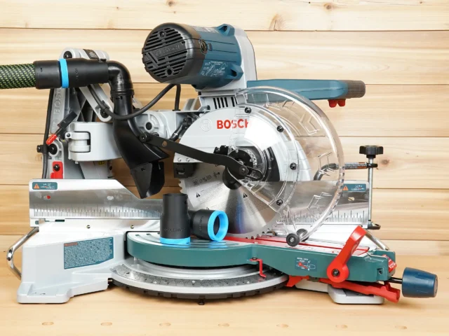 Black 36mm hose adapter with blue ring installed on a Bosch 10-inch glide miter saw dust port, second adapter on the table