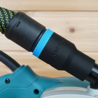 Black hose adapter with blue band attached to Makita belt sander dust port, connected to green and black braided hose