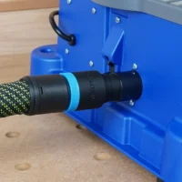 Black ToolCurve hose adapter with blue collar joining a braided vacuum hose to the blue Kreg Foreman dust port