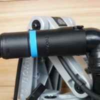 Black hose adapter with blue identification band attached to Bosch glide miter saw dust port, connected to green and yellow braided hose