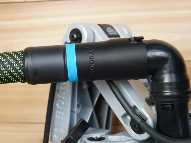 Black hose adapter with blue identification band attached to Bosch glide miter saw dust port, connected to green and yellow braided hose