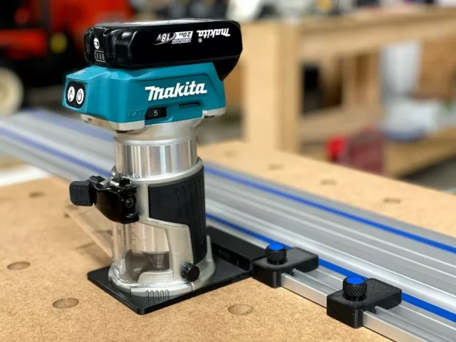 Kreg ACS limit stop mounted on a track saw guide rail next to a Makita router, showing the black cap and aluminum base with adjustment knob