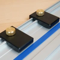 Two black aluminum limit stops with brass knurled knobs mounted on a Kreg track saw rail