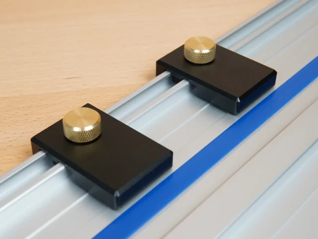 Two black aluminum limit stops with brass knurled knobs mounted on a Kreg track saw rail