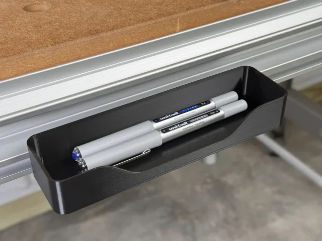 Black plastic pencil and storage tray mounted on Festool MFT/3 table t-track, holding pens and markers