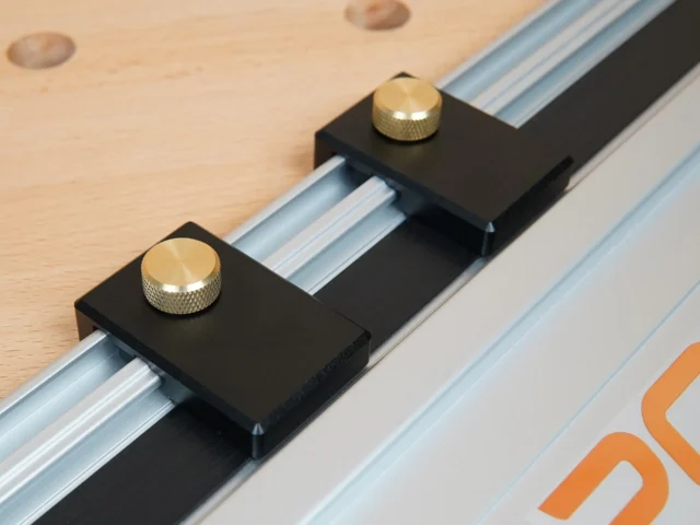 Two black aluminum limit stops with brass knurled knobs mounted on a PowerTec track saw guide rail