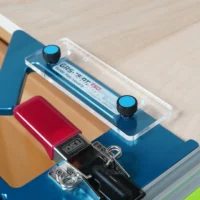 Blue anti-tip support tab under a TSO GRS-16 PE guide rail square's clear acrylic arm on a workpiece edge
