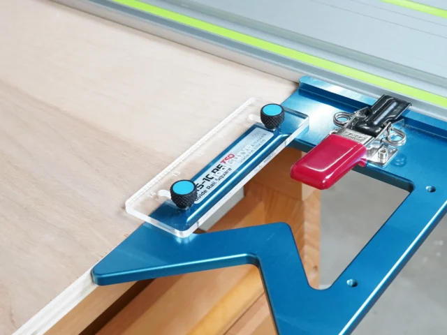 TSO guide rail support tab attached to blue aluminum guide rail square mounted on Festool track saw rail, red tab visible with thumb screw attachment