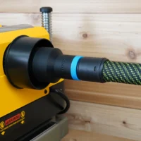 Black hose adapter with blue band attached to yellow Dewalt planer, connected to green braided hose