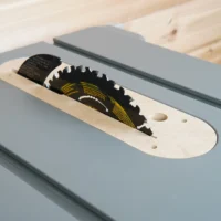 MDF zero clearance insert seated in a Dewalt 8-1/4 in. table saw with raised blade and riving knife through the slot