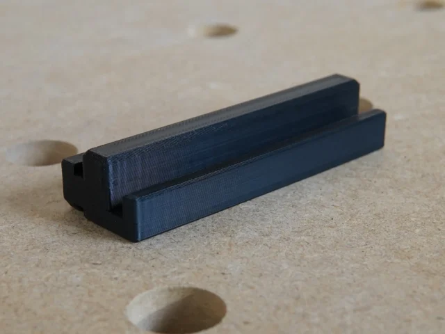 Black 3D-printed rail square holder with dual slots, designed to fit into an MFT/3 table t-track