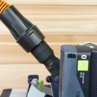 Black adapter with orange-striped hose attached, mounted on a Festool dust extractor with blue quick-connect port