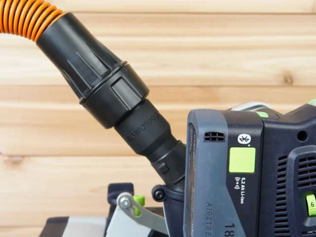 Black adapter with orange-striped hose attached, mounted on a Festool dust extractor with blue quick-connect port