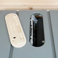 Cream-colored zero clearance insert and black interior insert side by side on gray Dewalt table saw top