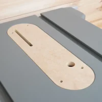 Natural wood zero clearance insert with slot and mounting holes, fitted in gray Dewalt table saw insert ring
