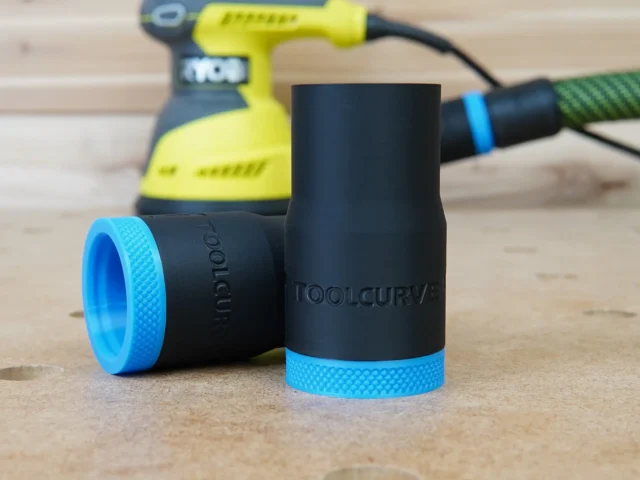 Black ToolCurve hose adapter with blue grip rings, shown disassembled in foreground with Ryobi sander blurred in background