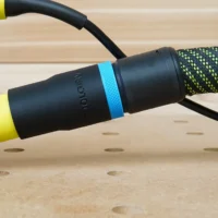 ToolCurve hose adapter with blue band attached to a Ryobi sander dust port, connected to a braided hose