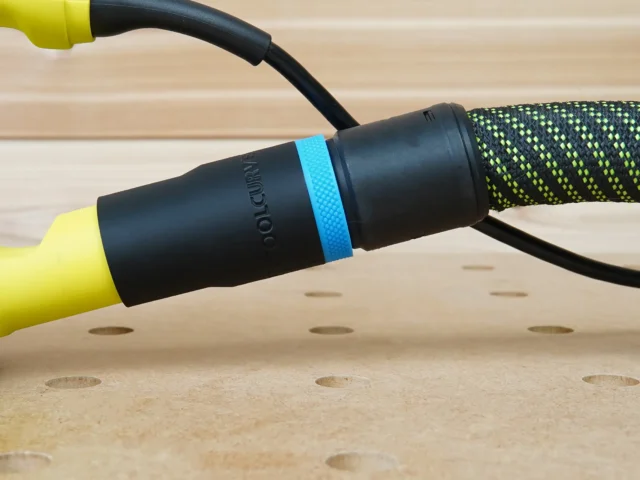 ToolCurve hose adapter with blue band attached to a Ryobi sander dust port, connected to a braided hose
