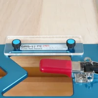 TSO guide rail square anti-tip support tab mounted on a blue track saw rail, showing two blue knobs and a red support block beneath the square