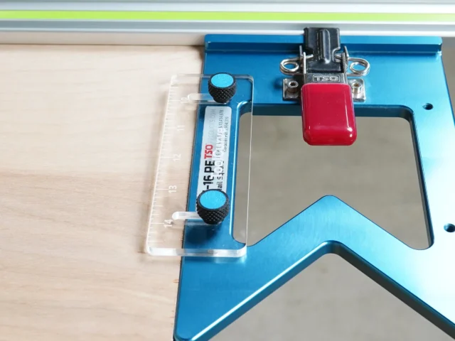 TSO guide rail square anti-tip support tab mounted on blue aluminum rail, with red clamp and acrylic support visible