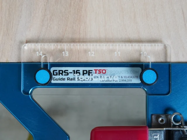 TSO Guide Rail Square Anti Tip Support Tab mounted on a blue guide rail square, showing the clear acrylic top with inch markings and two cyan support pegs