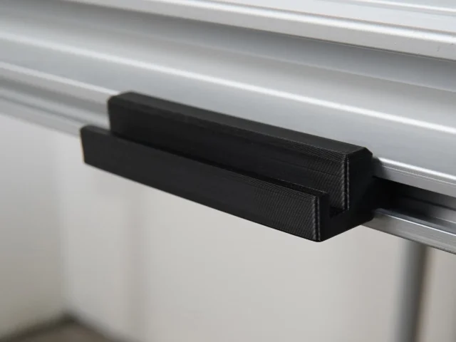 Black plastic rail square holder clipped onto the side of an MFT/3 table's t-track profile