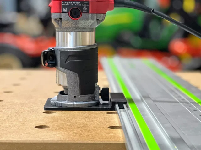 Avid Power compact router mounted on black ToolCurve adapter base, positioned on Festool-style guide rail over wooden workpiece
