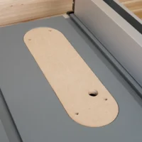 Beige MDF zero clearance insert for DeWalt table saw, positioned in the saw table with mounting holes and blade opening visible