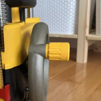 Yellow stubby handle with knurled grip attached to a DeWalt planer height adjustment crank, shown next to a ruler for scale