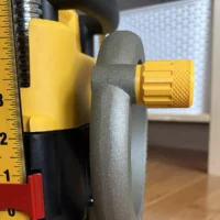 Gray knobbed stubby handle with yellow knurled knob attached to DeWalt planer crank, shown next to tape measure for scale