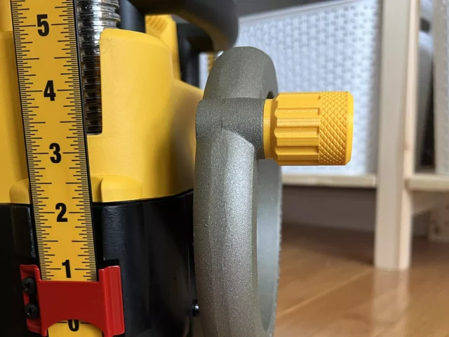 Gray knobbed stubby handle with yellow knurled knob attached to DeWalt planer crank, shown next to tape measure for scale