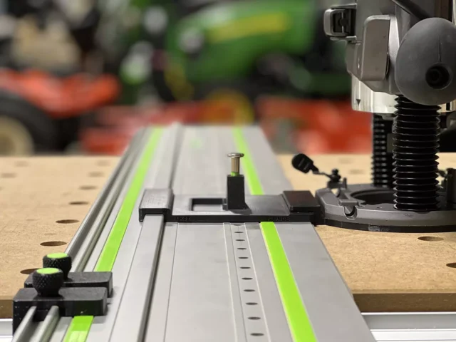 Skil RT1322 plunge router adapter mounted on Festool track rail with LR32 plate, spring-loaded knob, and guide rail stops for hole drilling