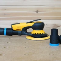 Black and blue ToolCurve hose adapters standing beside a Mirka Deros sander with hose connected, on a workbench