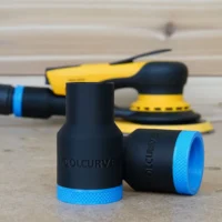 Black ToolCurve hose adapter with blue grip ring, shown with Mirka sander and other tools on wood surface