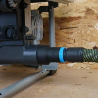 Black hose adapter with blue band attached to SKIL worm drive table saw dust port, connected to green and yellow braided hose