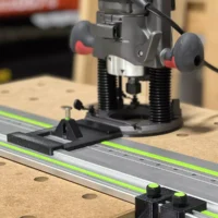 Skil RT1322 plunge router mounted on LR32 guide rail with hole drilling adapter and positioning stops on wood workbench