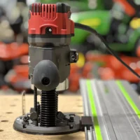 Skil RT1322 plunge router attached to LR32 rail adapter with red motor head and black threaded base, positioned on green Festool-style guide rail