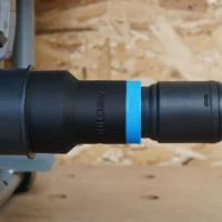 Black hose adapter with blue band attached to SKIL worm drive table saw dust port, green braided hose connected