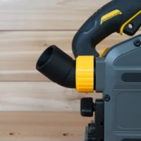 Yellow and black No Snag Dust Port adapter attached to a DeWalt track saw, with black hose angled upward from the adapter
