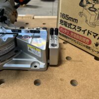 Makita LS610DZ miter saw with extension arms attached, viewed from above on pegboard workbench