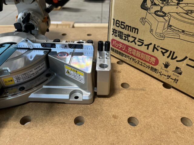 Makita LS610DZ miter saw with extension arms attached, viewed from above on pegboard workbench