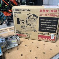Makita LS610DZ miter saw in original Japanese packaging, shown in cardboard box next to base unit on work table