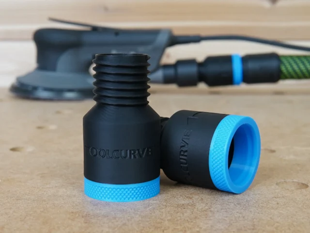 Two black hose adapters with blue knurled grip rings, one showing threaded male end and one showing female port, displayed on a workbench