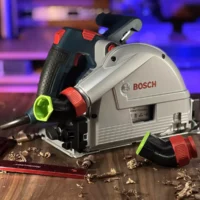 No Snag dust port adapter mounted on a Bosch track saw, showing the upward-angled hose connection with removable red collar