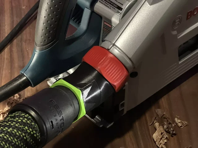Red and green no-snag dust port adapter mounted on a Bosch track saw, with vacuum hose attached below